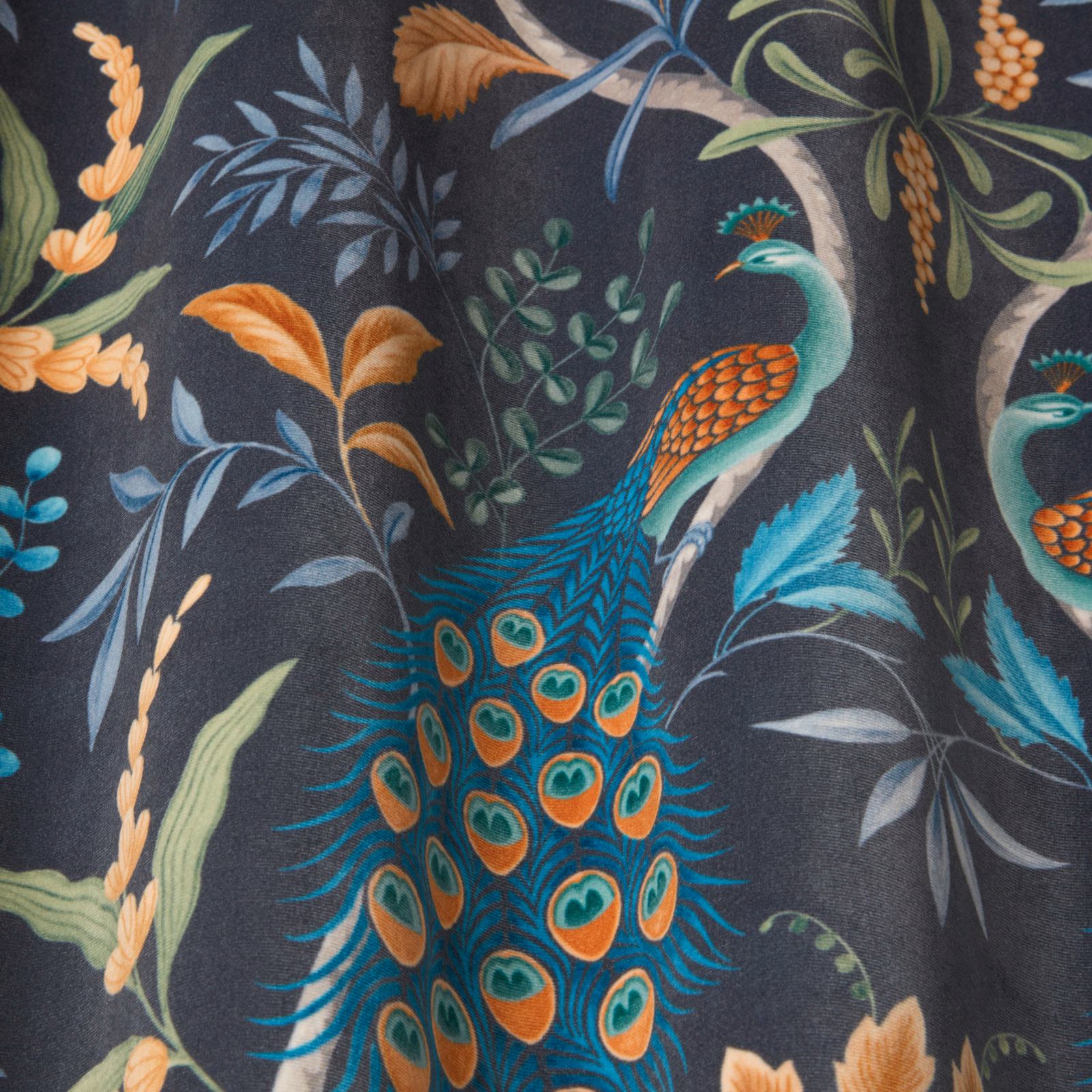 Peacock print fabric on a deep charcoal ground with teal, orange and sage foliage