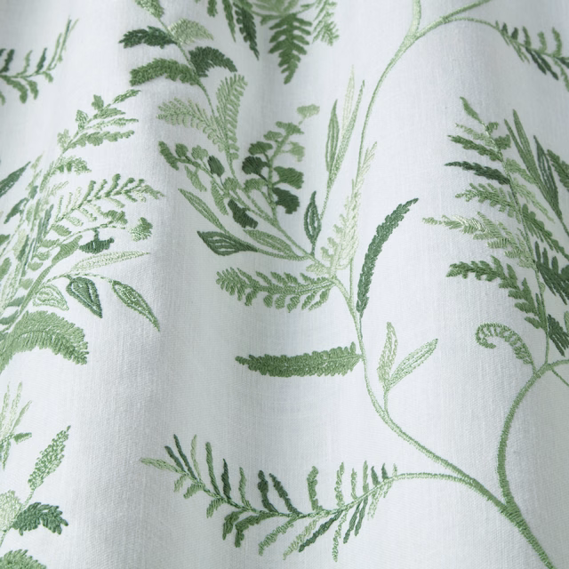 Embroidered green leaf trail on a pale ivory woven fabric swatch