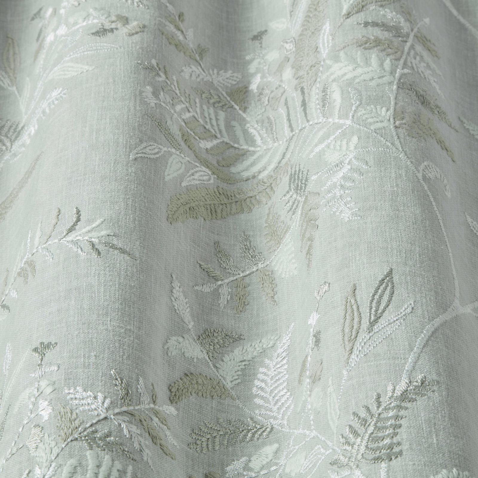 Pale sage-green botanical fabric with woven leaf motif and soft sheen