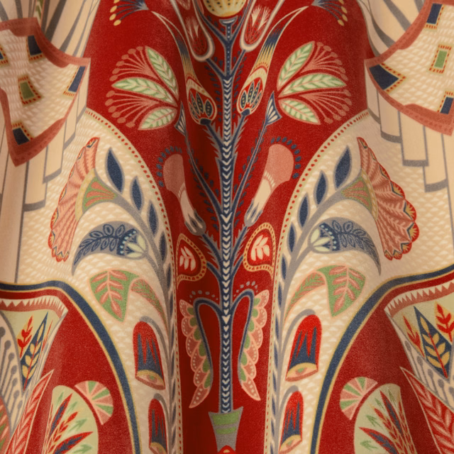 Close-up of garnet red patterned fabric with cream, navy and green motifs