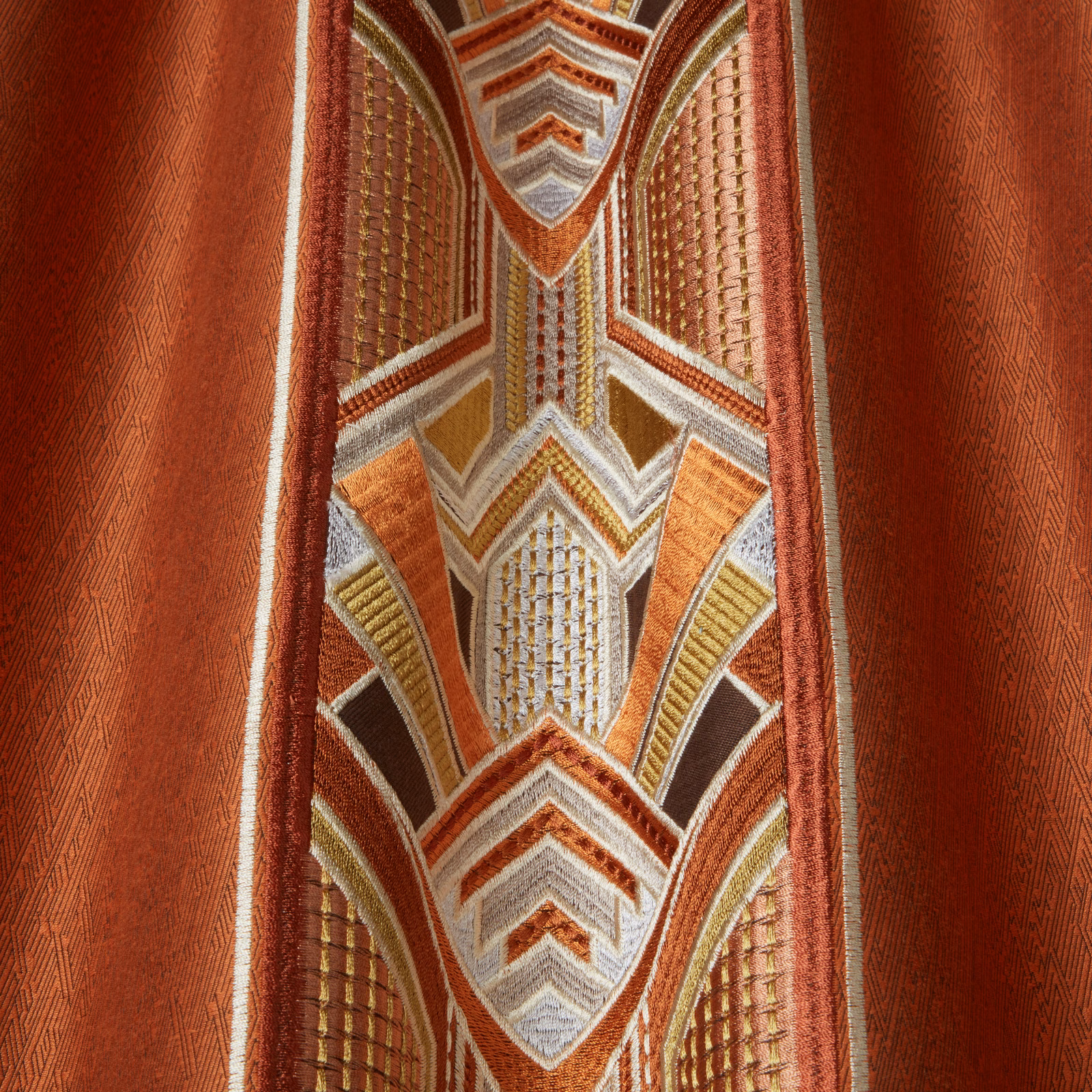 Geometric amber and rust woven fabric with cream accents and a textured red ground