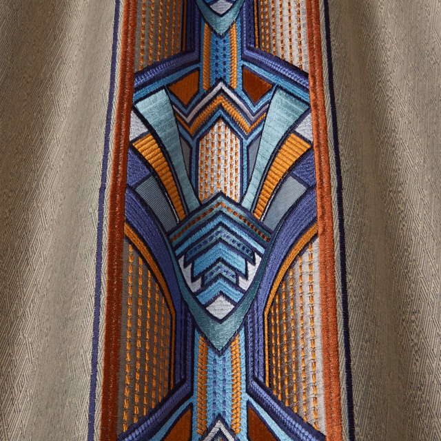Close-up of geometric woven fabric in navy, teal, aqua and orange with a textured sheen