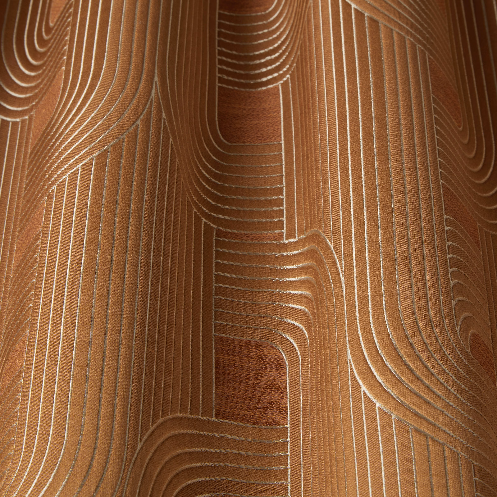 Amber geometric fabric with flowing cream linework and a soft woven sheen