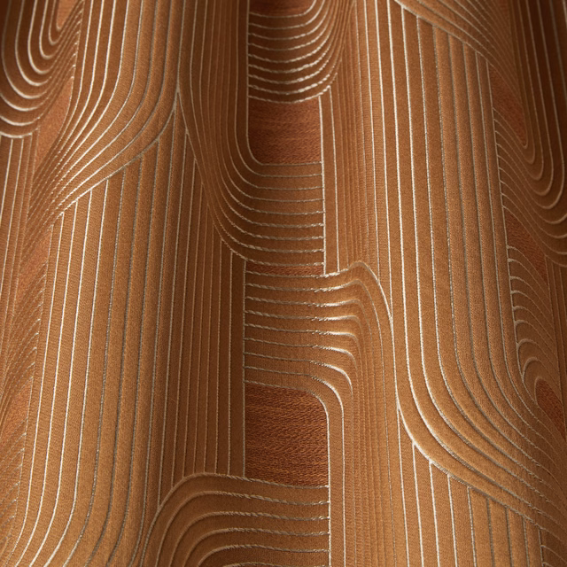 Amber geometric fabric with flowing cream linework and a soft woven sheen