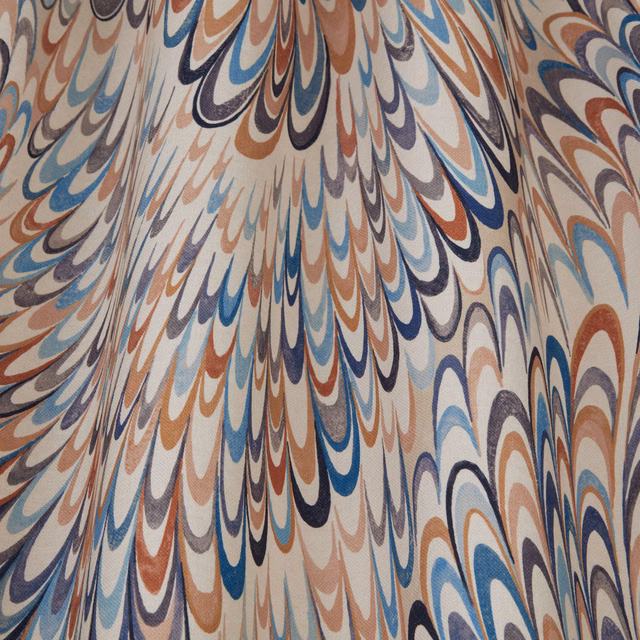 Printed fabric swatch with feathered wavy arcs in blue, terracotta and taupe on a cream ground