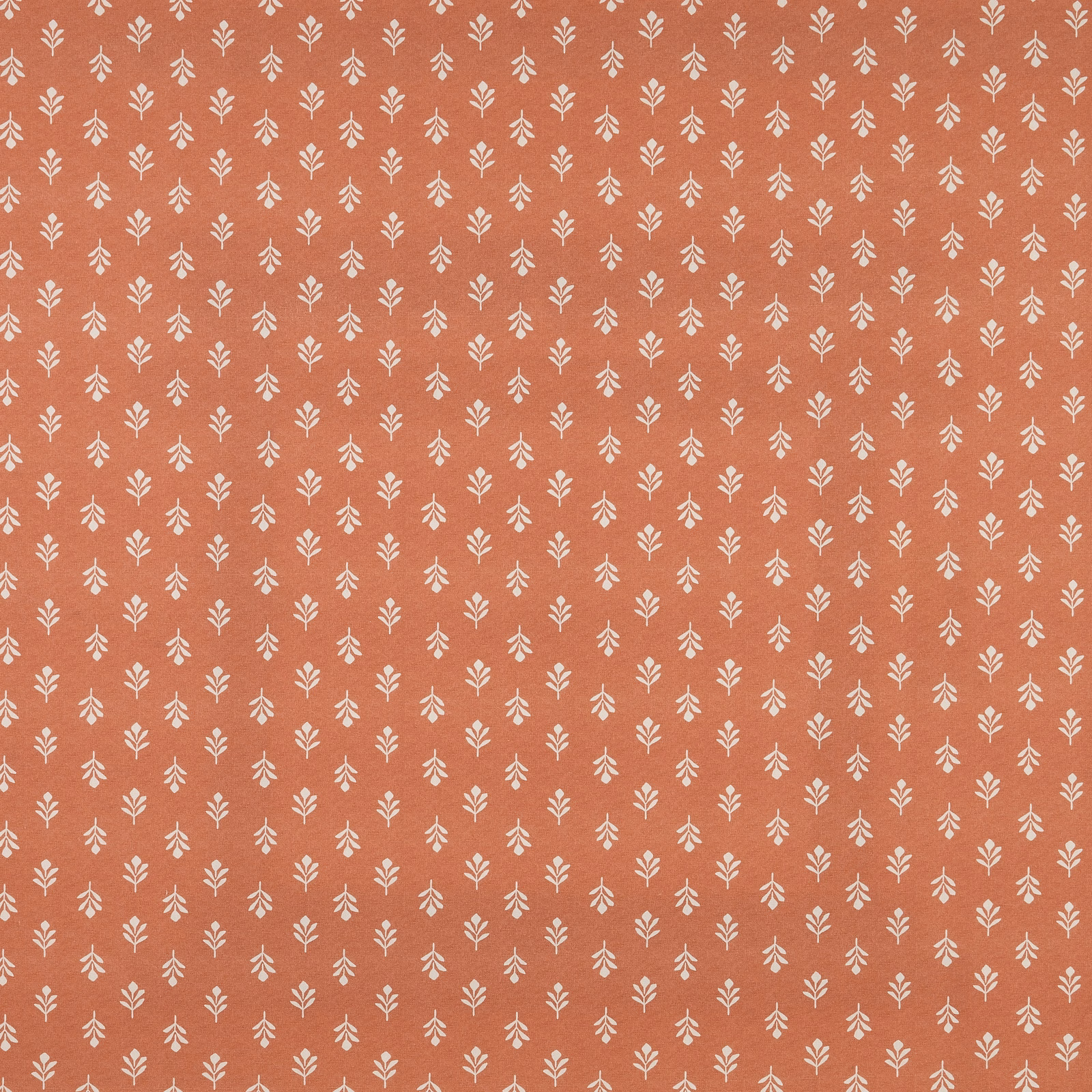 Terracotta cotton fabric with tiny cream leaf sprigs in a small repeating chintz pattern