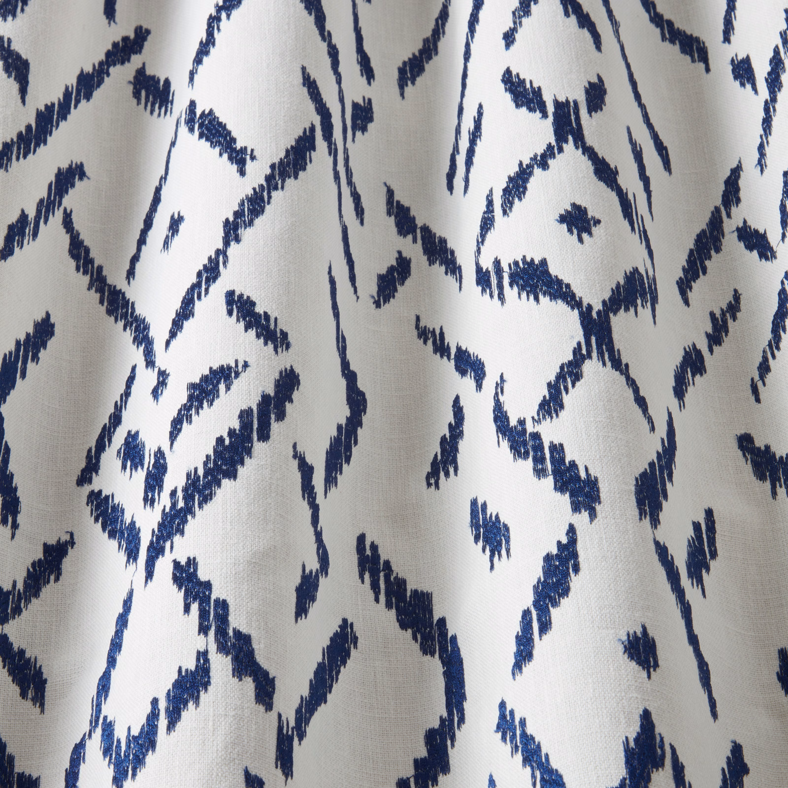 Blue zigzag geometric cotton fabric on a pale background, close-up swatch