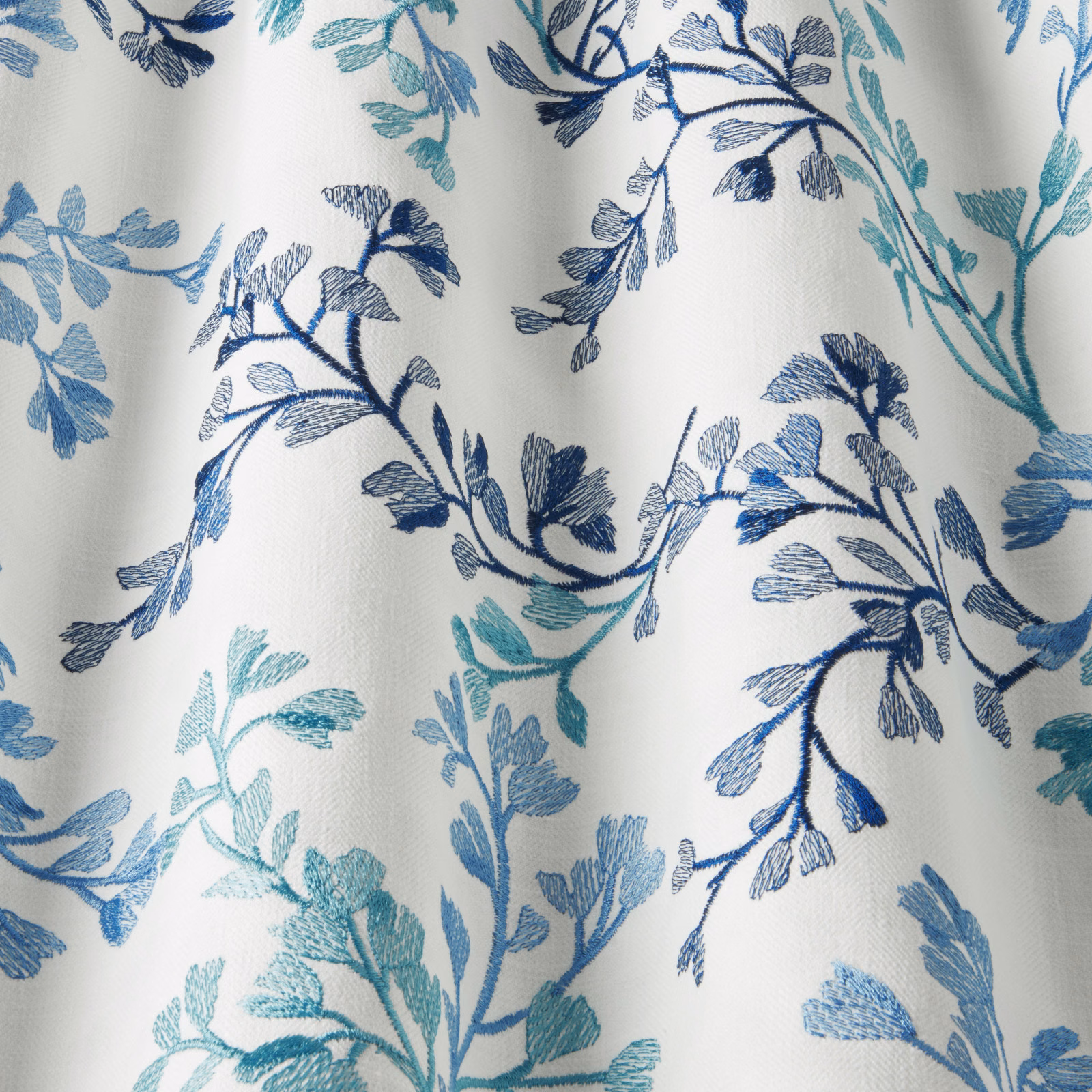Pale cotton fabric with trailing cornflower blue and teal leafy branches
