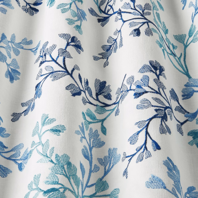 Pale cotton fabric with trailing cornflower blue and teal leafy branches