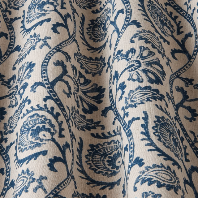 Close-up of cream woven fabric with large sapphire blue wavy damask motif