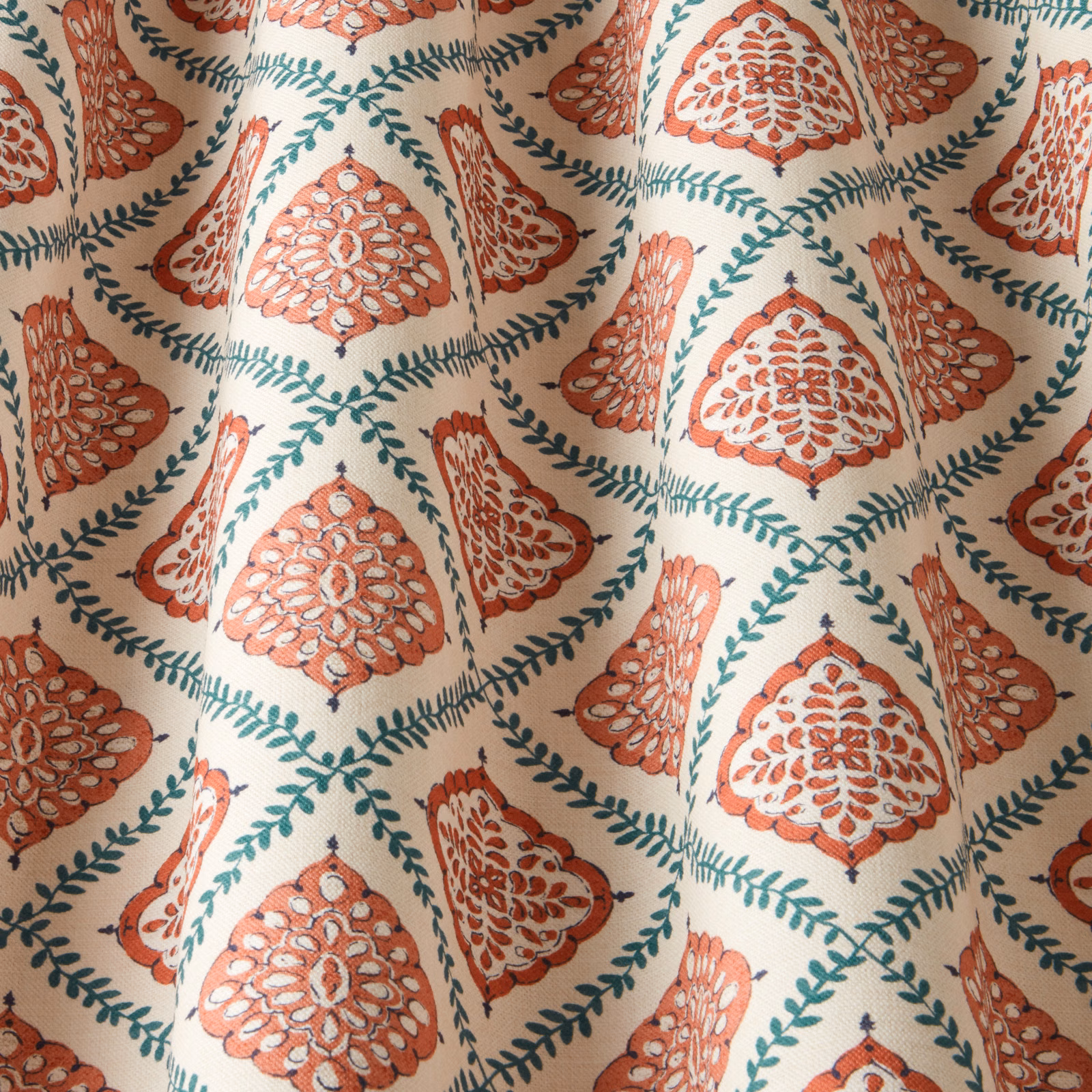 Terracotta and teal ornamental floral fabric on a cream ground, softly draped