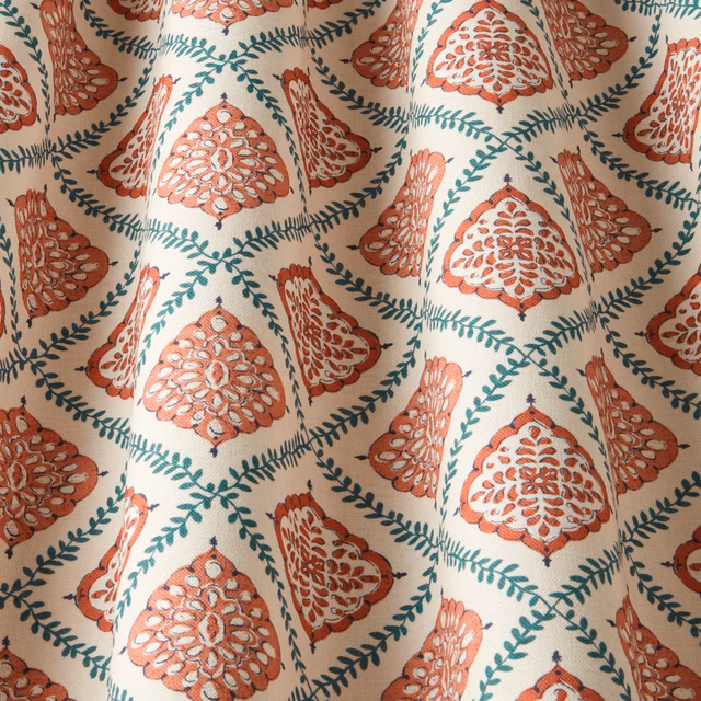 Terracotta and teal ornamental floral fabric on a cream ground, softly draped