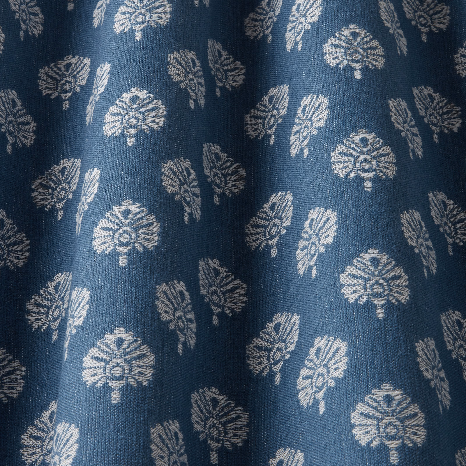 Deep sapphire woven fabric with pale repeating floral motifs and textured weave