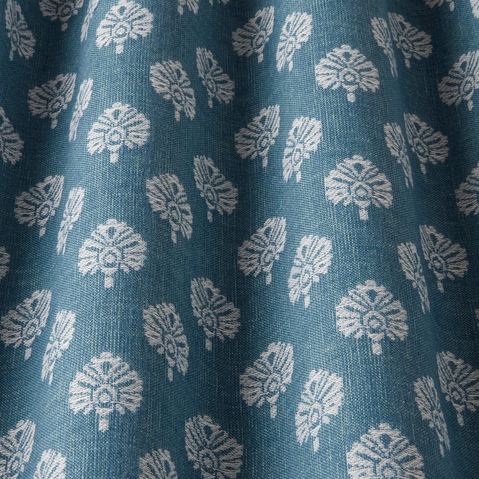 Teal woven fabric with small ivory botanical motifs and visible textured weave