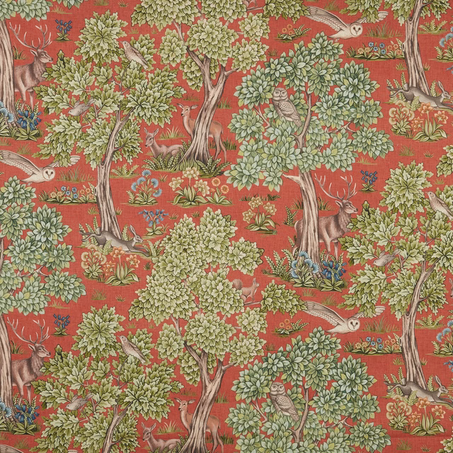 Woodland animal print fabric on a burnt terracotta red ground with leafy green trees