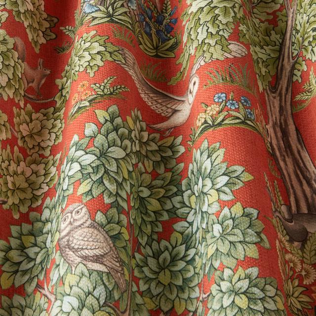 Red woven fabric printed with woodland leaves, birds and tree branches
