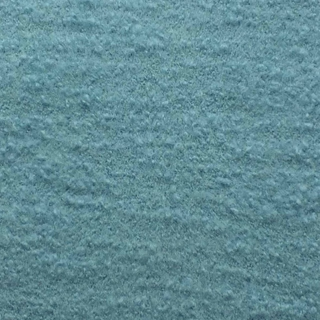 Close-up of muted blue-teal bouclé with a softly mottled, nubby texture
