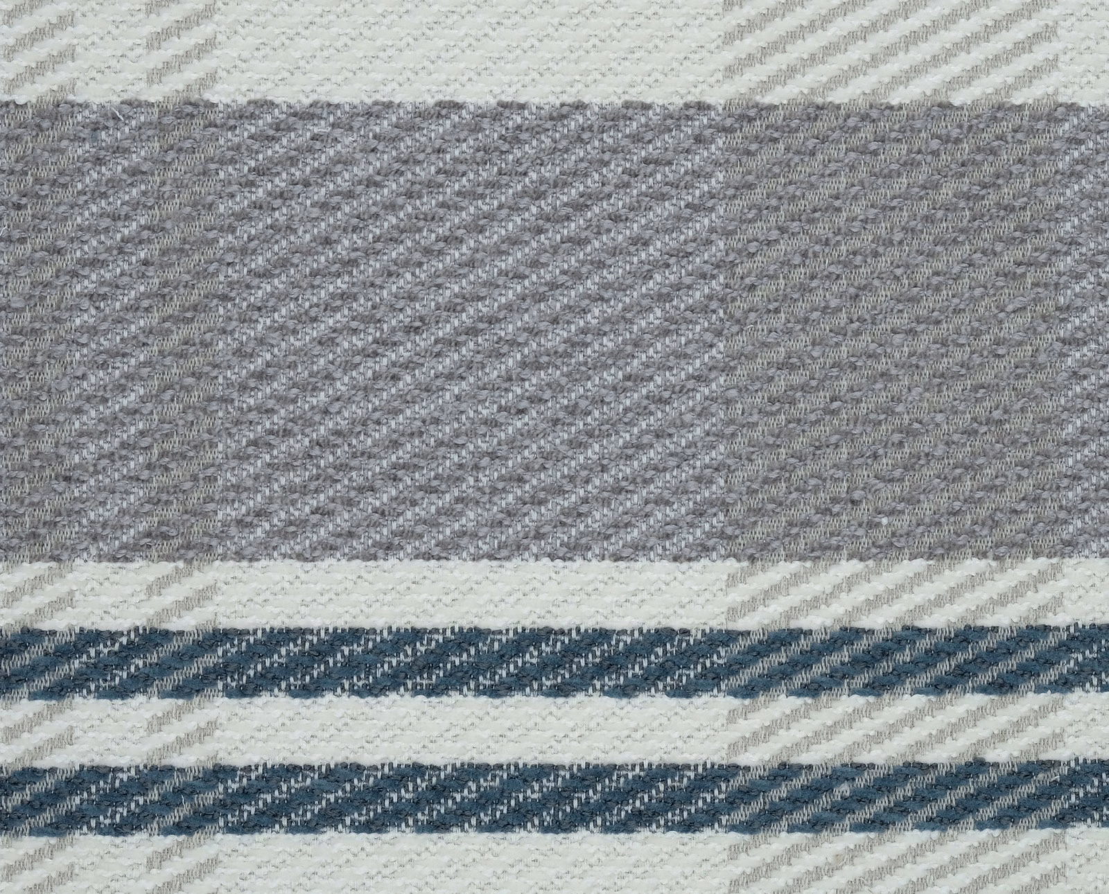 Close-up of a large petrol blue and ivory checked woven fabric with grey accents