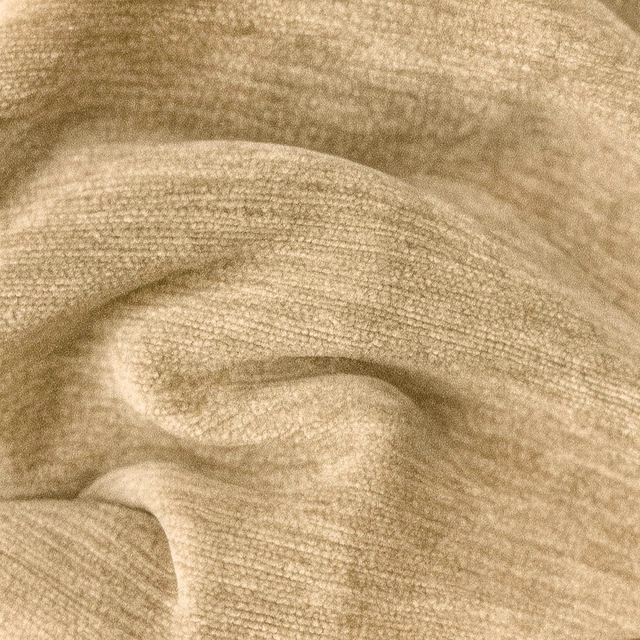 Close-up of warm beige woven plain fabric with soft folded texture