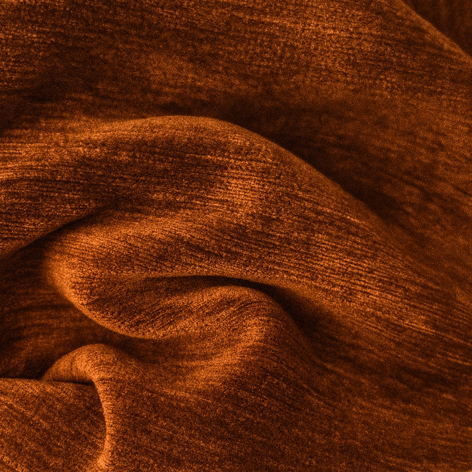 Close-up of deep burnt umber plain fabric with soft folded texture and coppery sheen