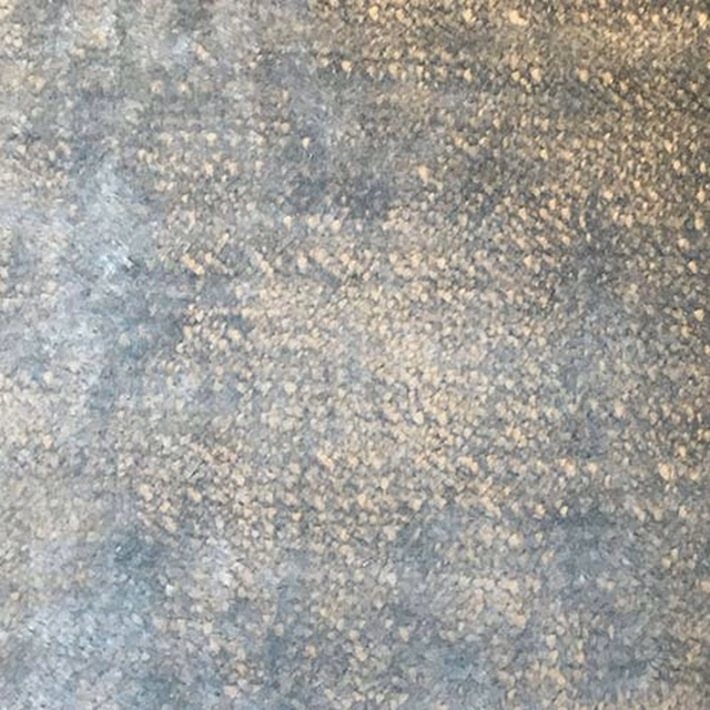 Close-up of a softly mottled mineral grey plain fabric with pale chalky flecks