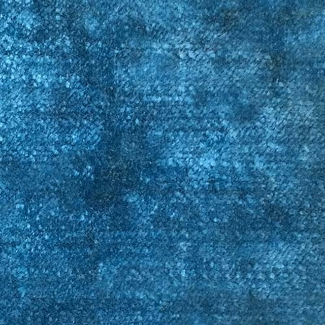 Close-up of deep peacock teal plain fabric with mottled velvet-like texture
