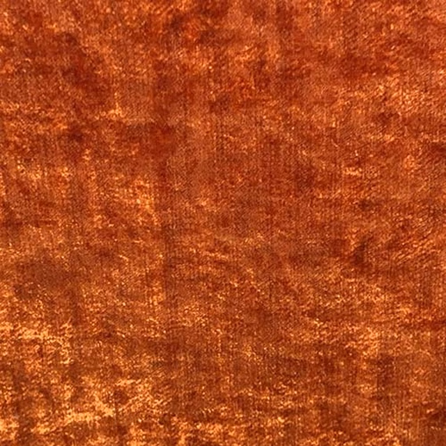 Close-up of burnished tangerine plain fabric with a plush, mottled texture