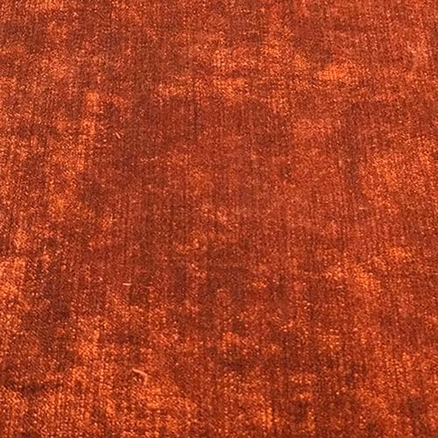 Close-up of a warm terracotta plain fabric with mottled coppery highlights and soft textured weave.