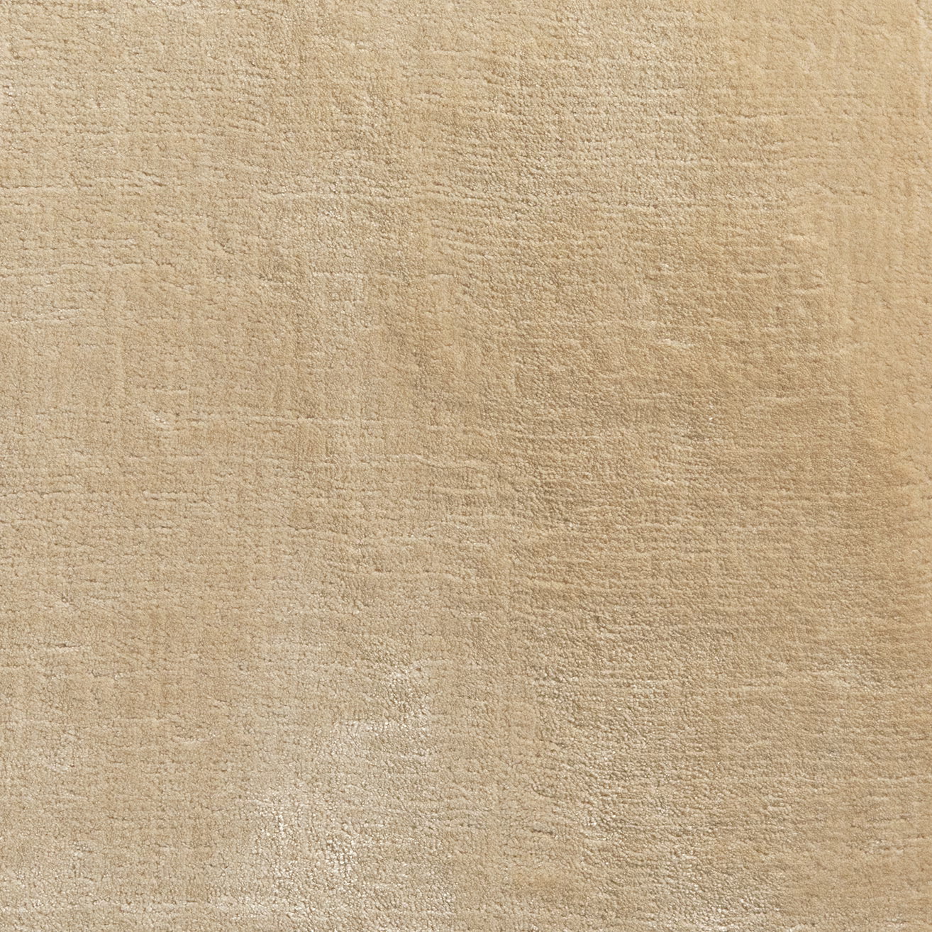 Warm wheat-beige carpet swatch with fine mottled texture and softly uneven shading