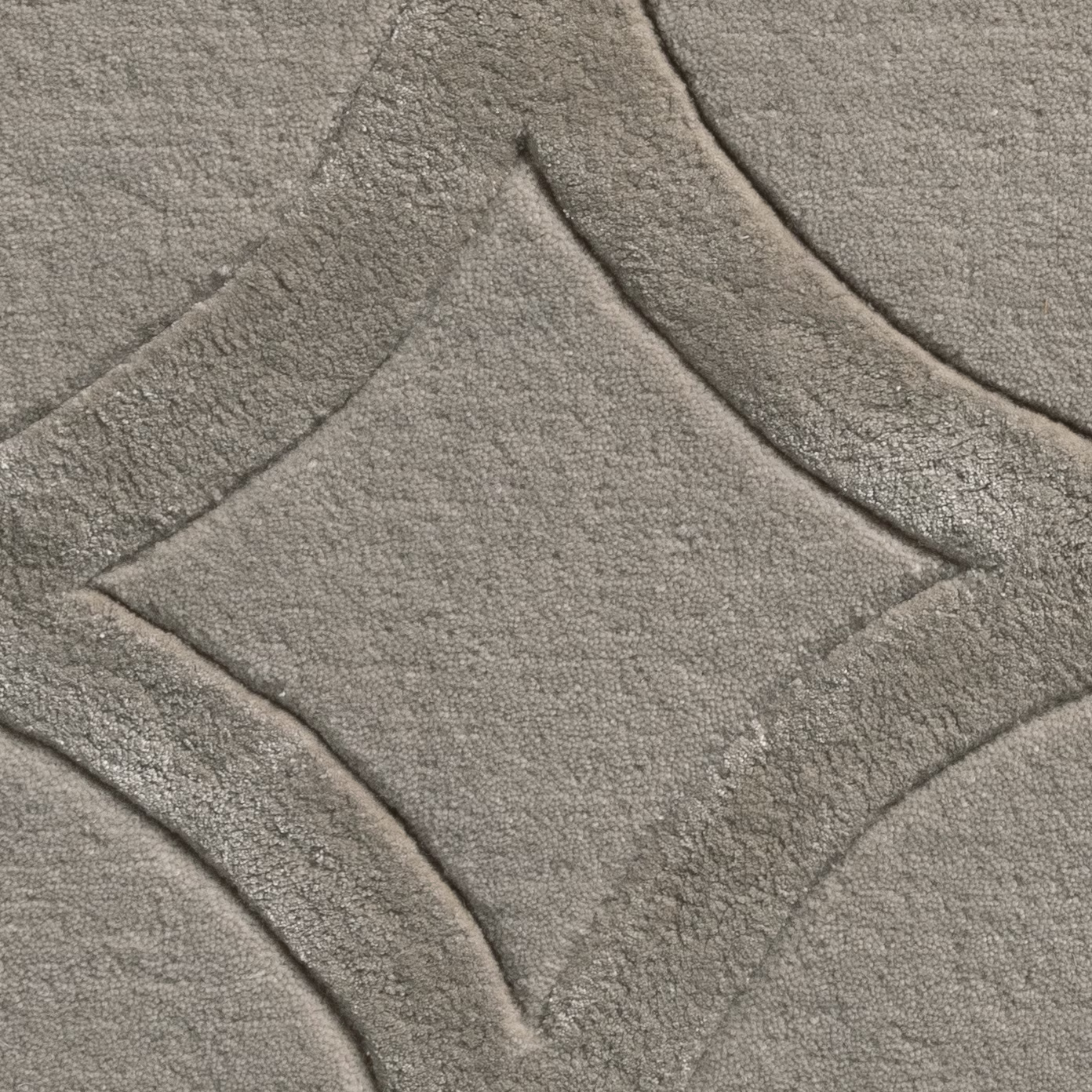 Close-up of cool pebble-grey carpet with plush texture and curved geometric bands