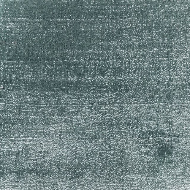 Close-up of muted duck egg blue-green carpet with dense mottled looped texture