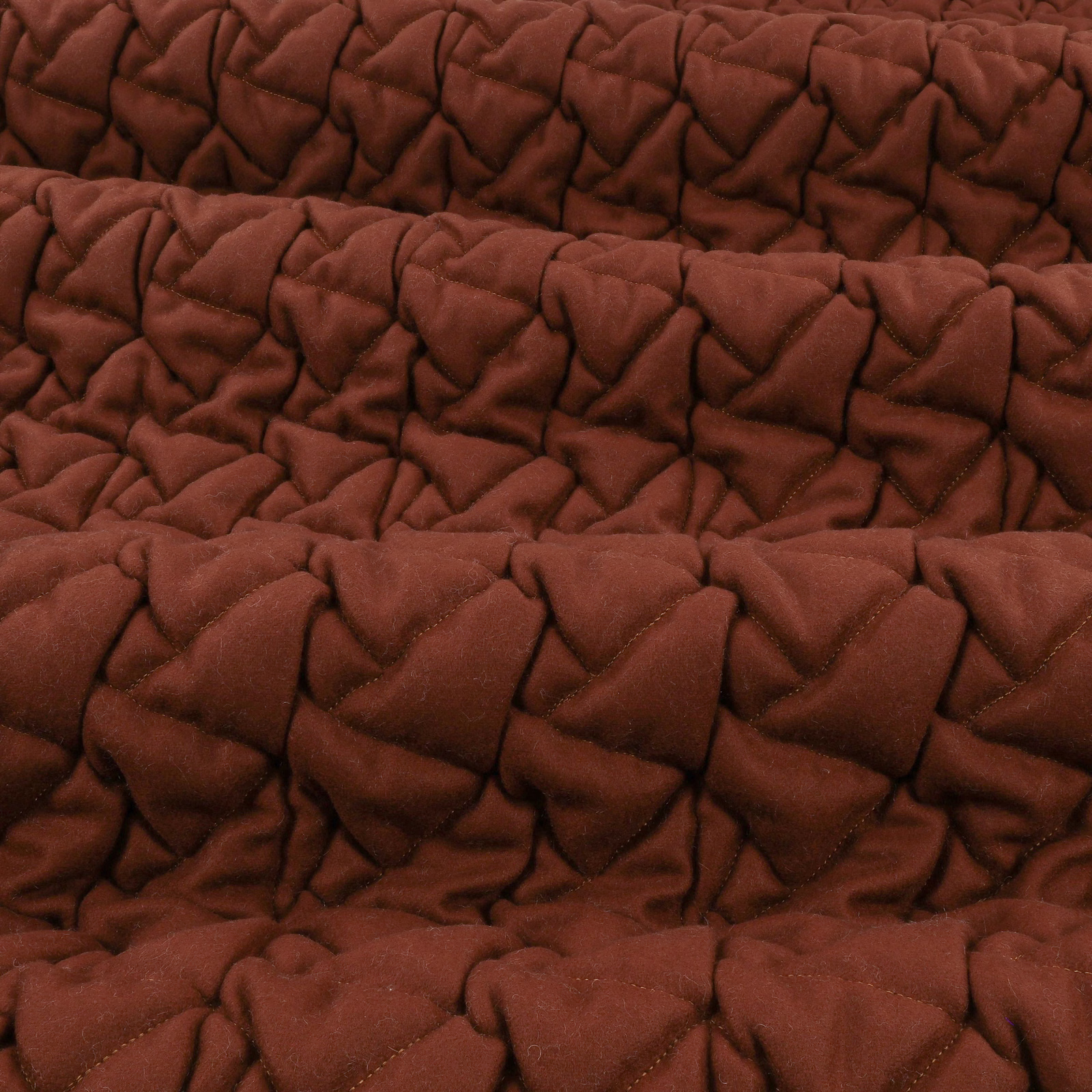 Deep conker-brown fabric with plush, irregular quilted folds and soft shadowed texture