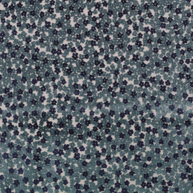 Close-up of muted teal fabric with navy floral clusters on a pale mottled ground