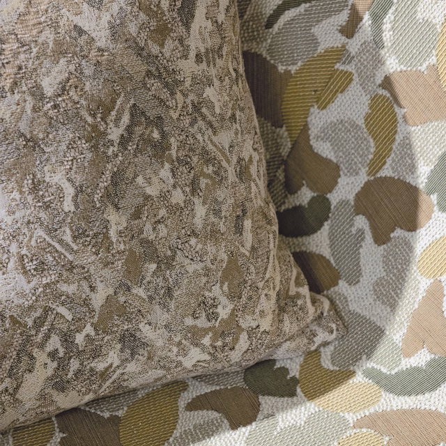 Warm buff woven fabric with mottled taupe markings and rounded abstract motifs