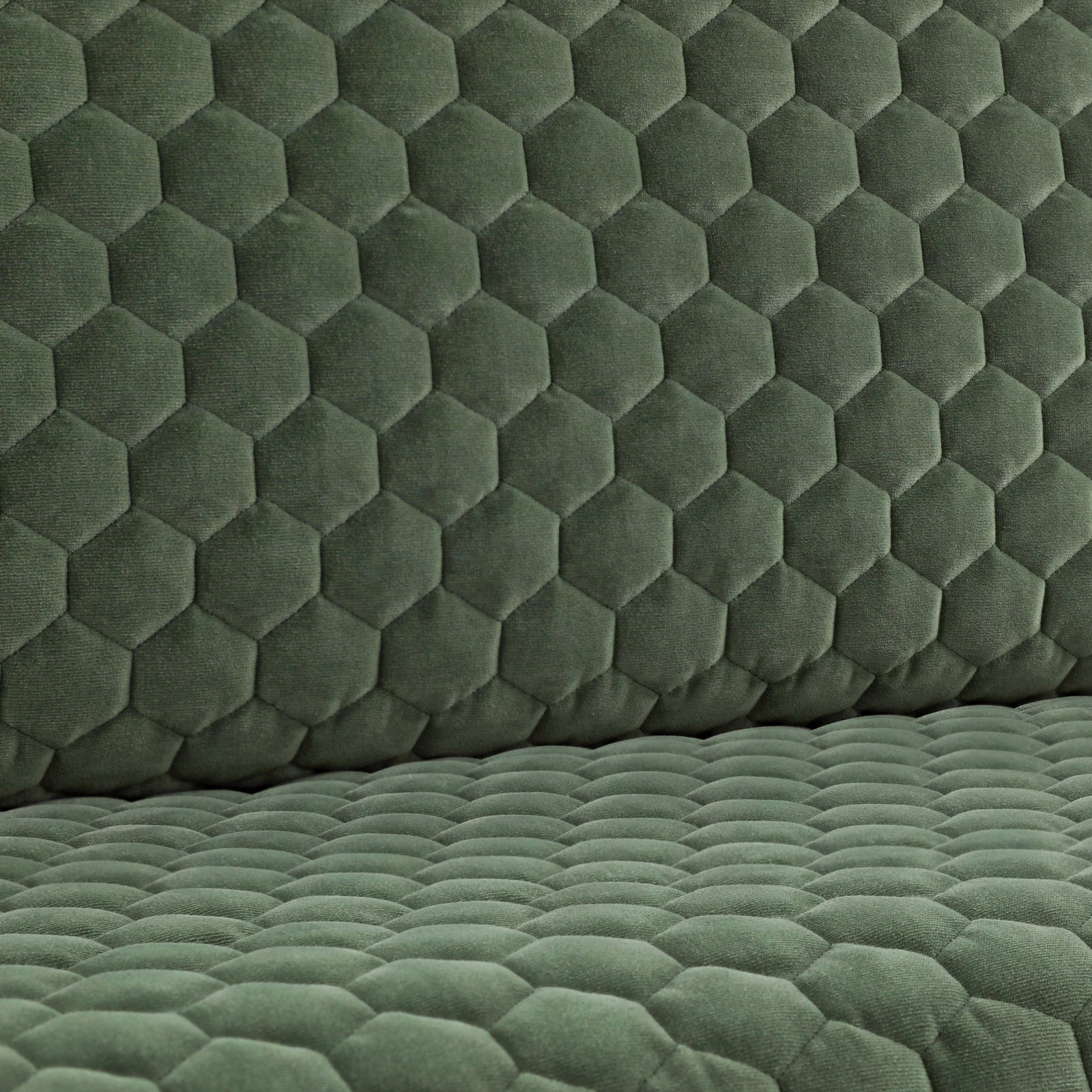 Muted eucalyptus-green quilted fabric with raised hexagonal cells and plush directional shading