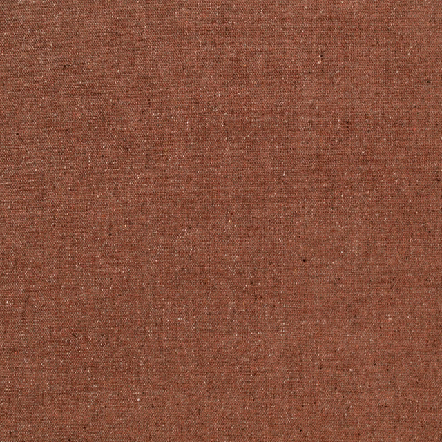 Close-up of rust terracotta woven fabric with fine pale flecks and subtle texture