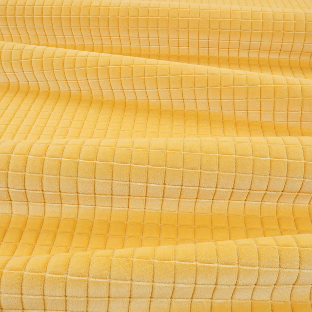 Close-up of warm custard-yellow fabric with a softly rippled square grid texture