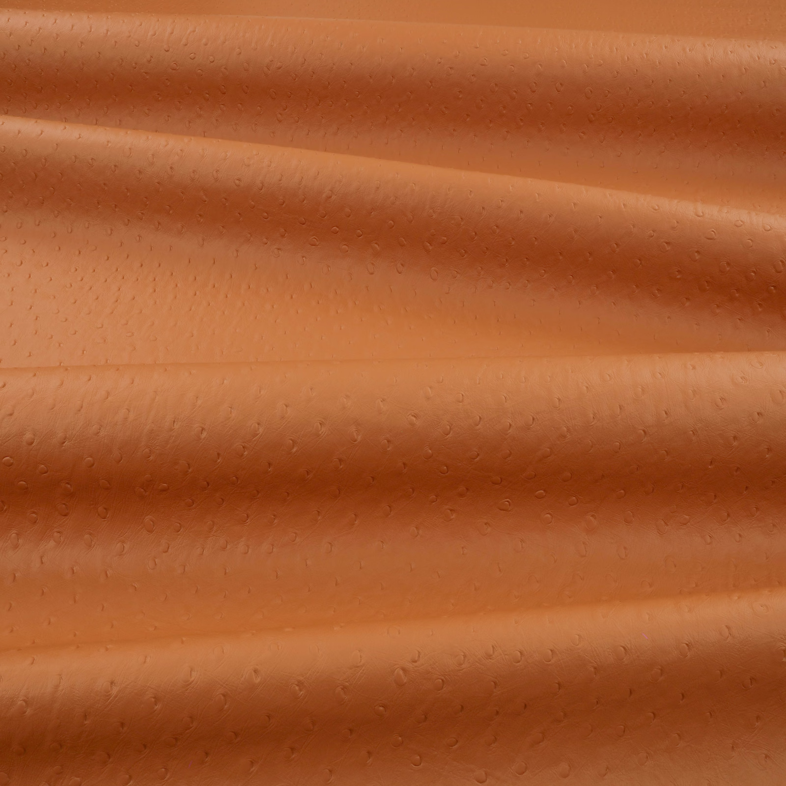Warm sweet-potato orange embossed upholstery textile with small ostrich-like dimples