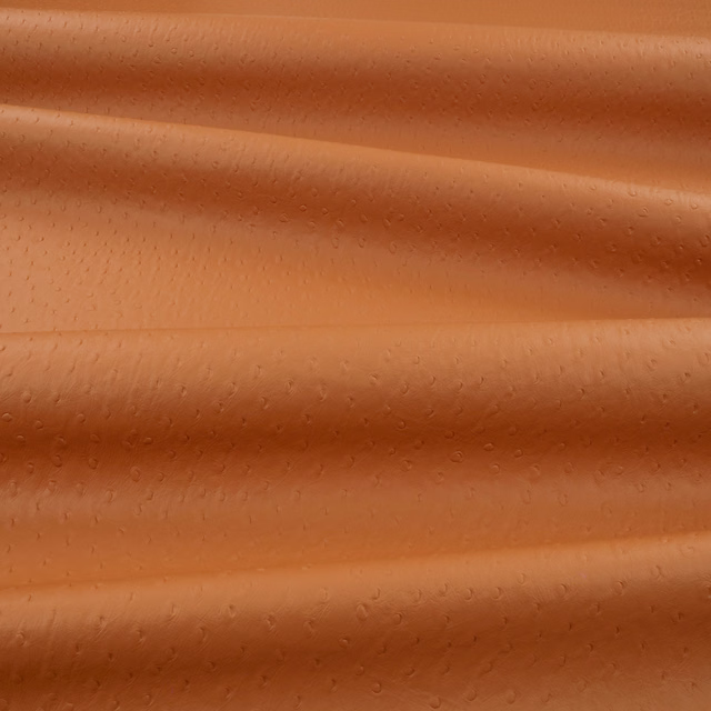 Warm sweet-potato orange embossed upholstery textile with small ostrich-like dimples