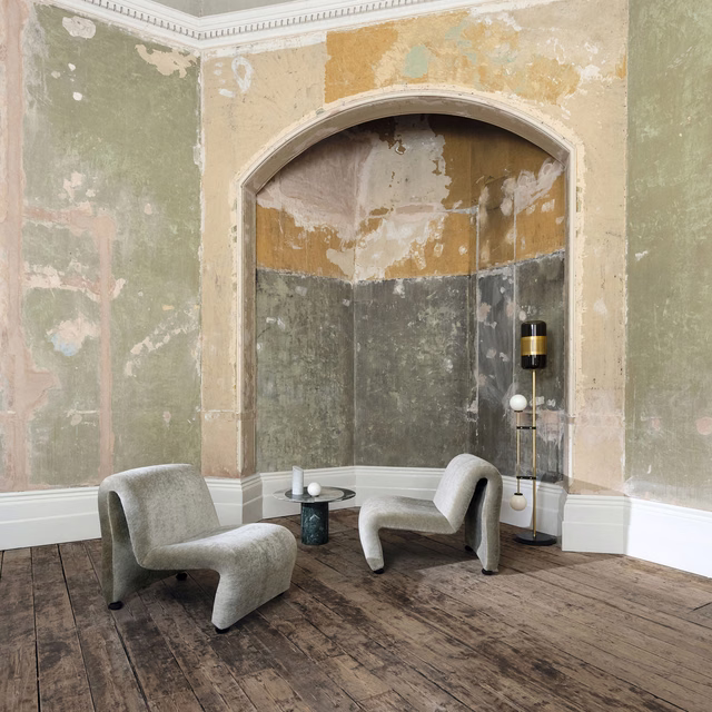 Muted putty-grey mottled upholstery on sculptural lounge chairs in a weathered room