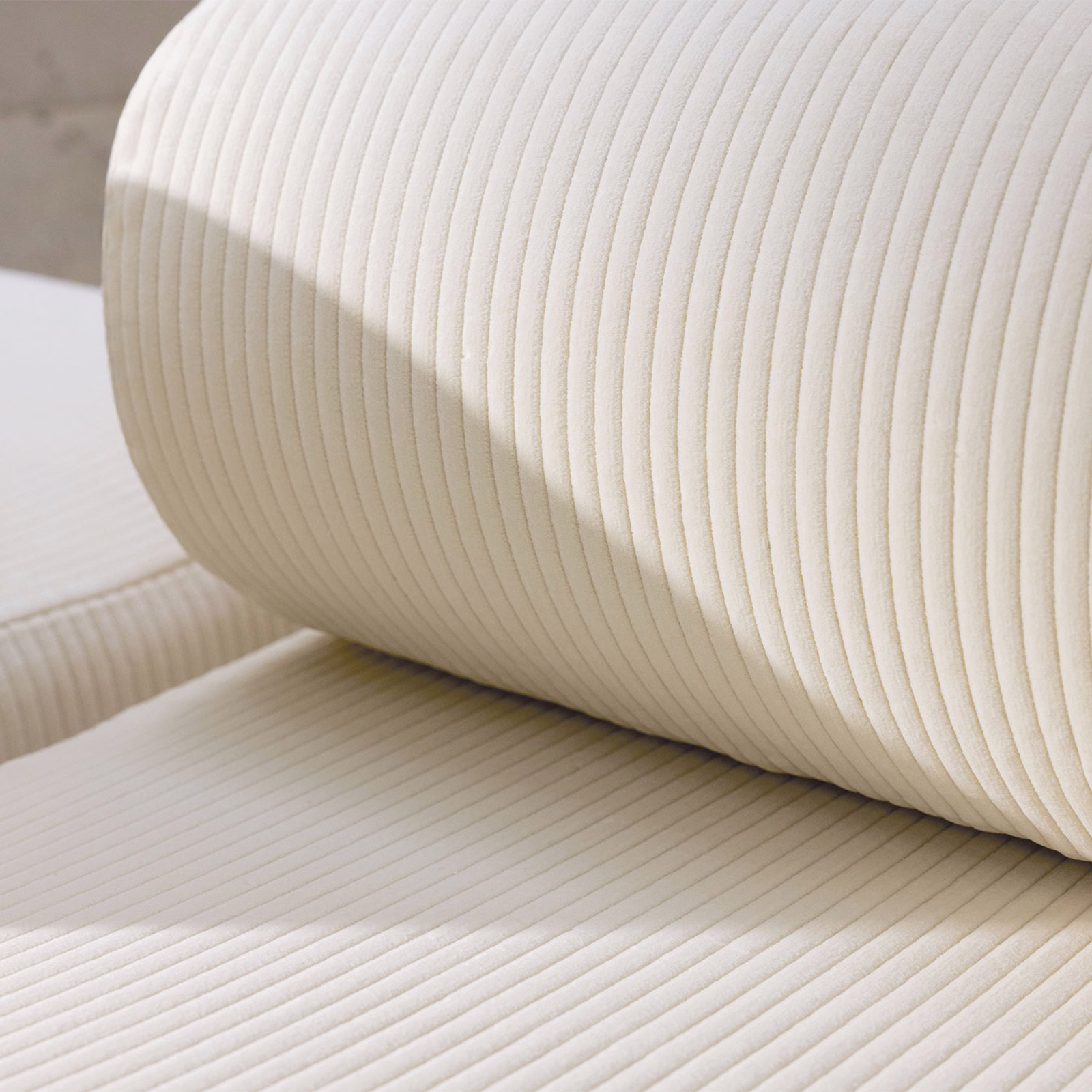 Warm ivory cream ribbed upholstery textile draped over a curved padded form