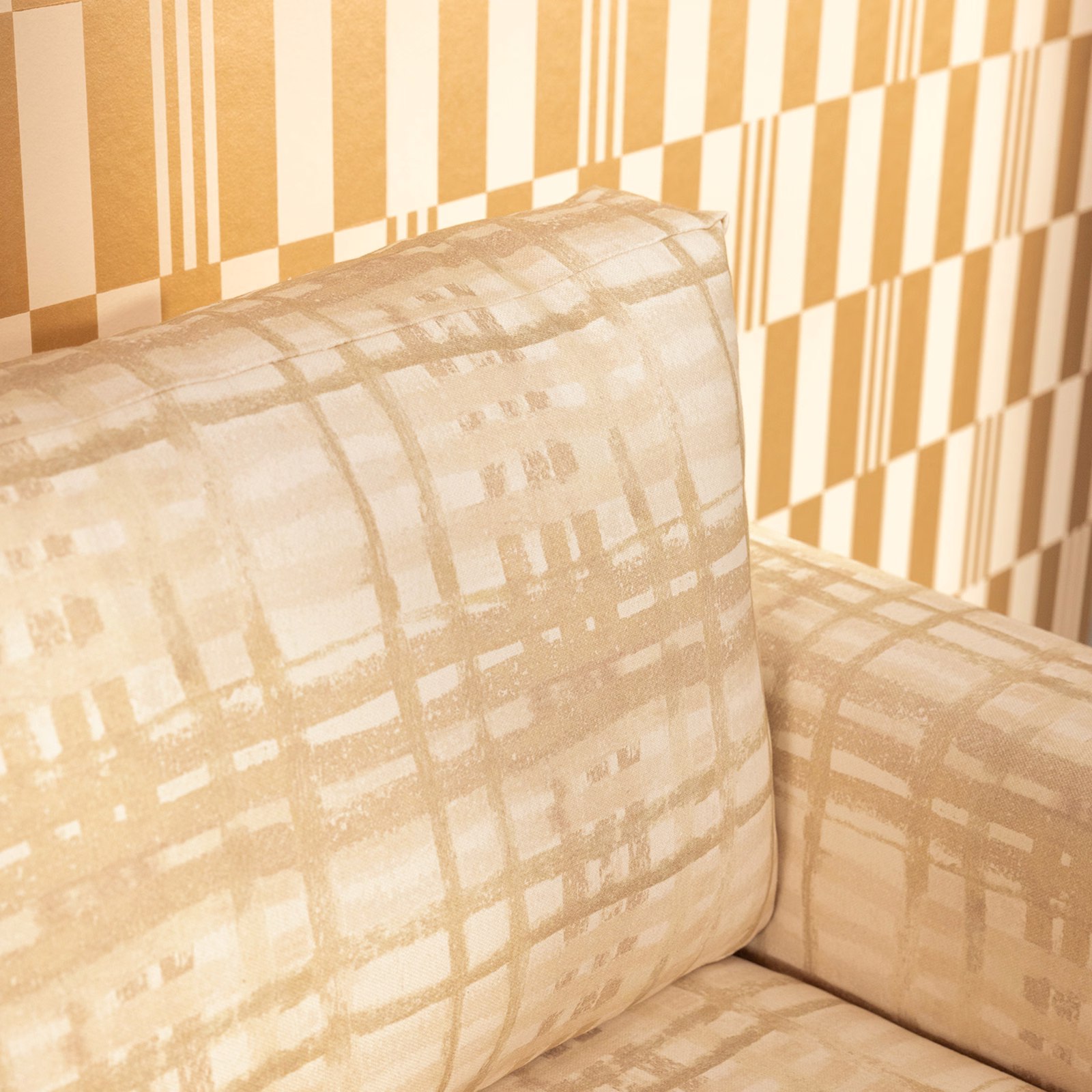 Warm natural beige upholstery with a softly broken abstract grid on a cushion