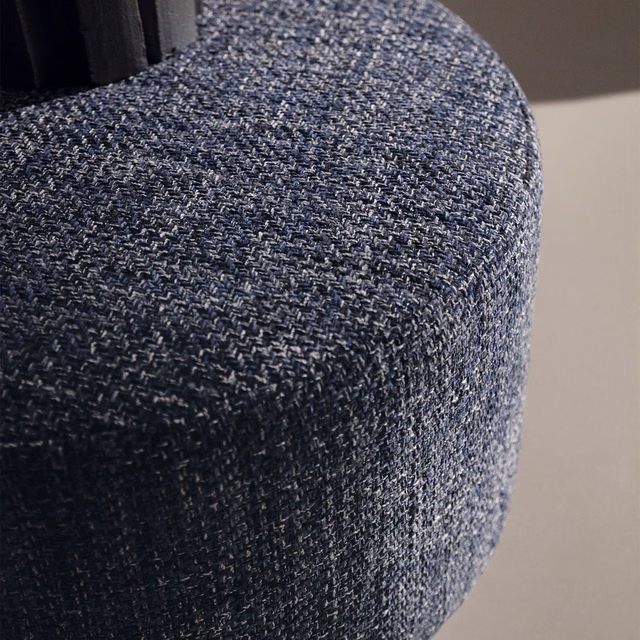 Close-up of indigo and grey flecked weave curving over an upholstered form