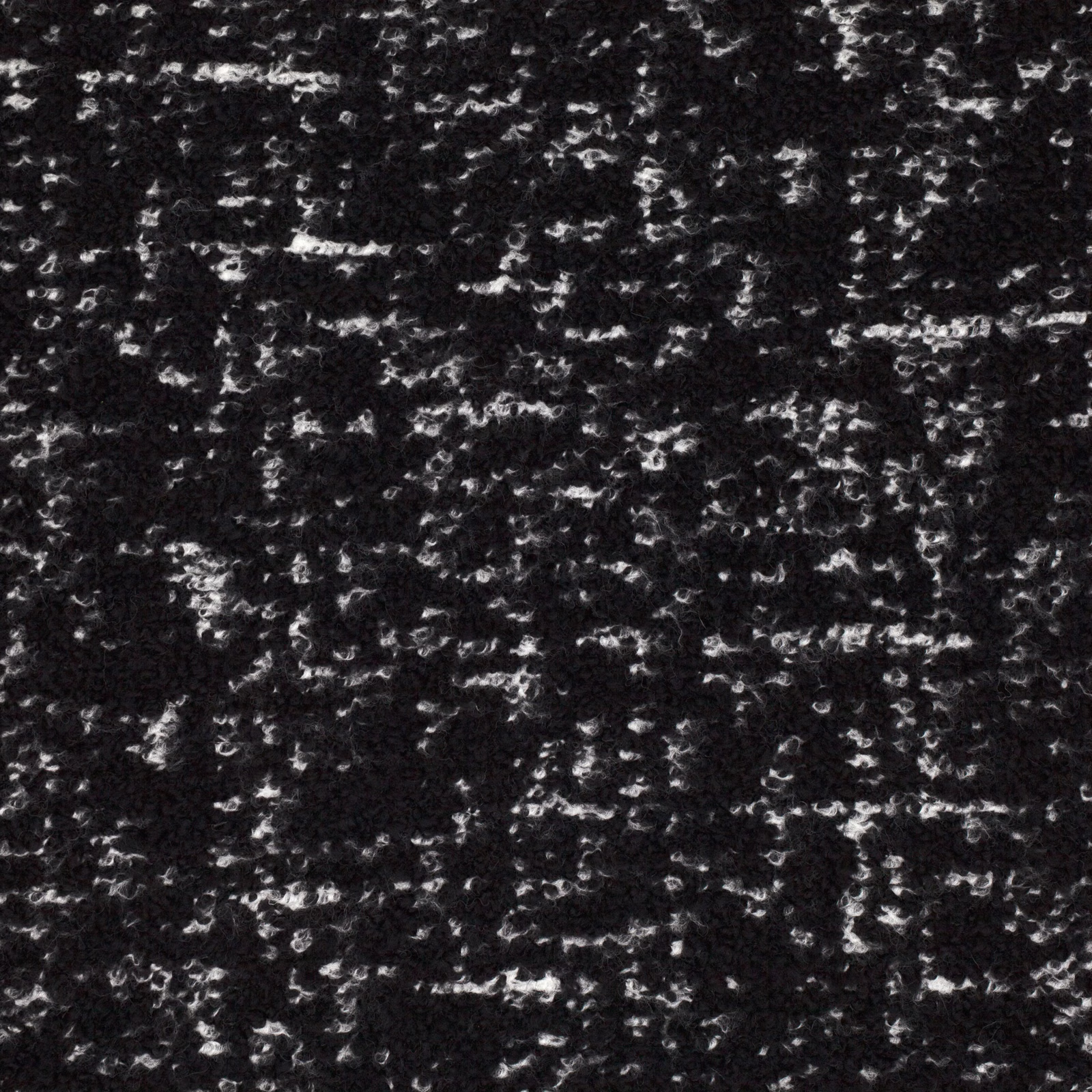 Black textile surface scattered with irregular white and grey flecks and nubby texture