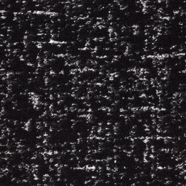 Black textile surface scattered with irregular white and grey flecks and nubby texture