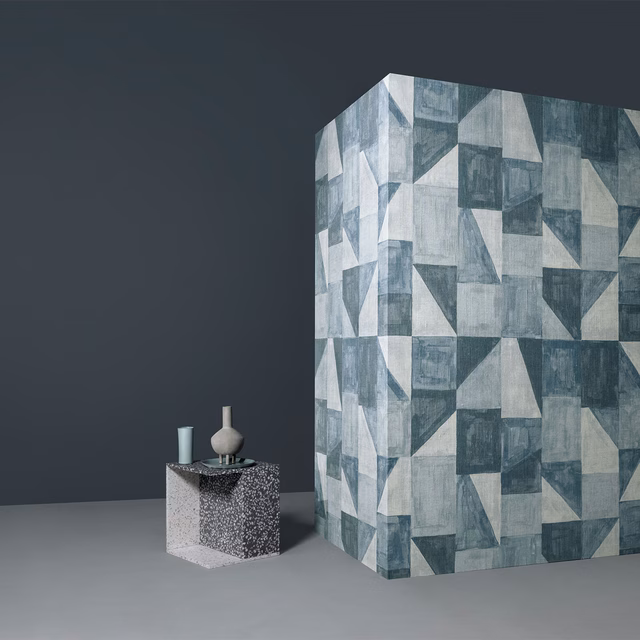Blue-grey geometric wall mural with weathered angular blocks in a staged interior