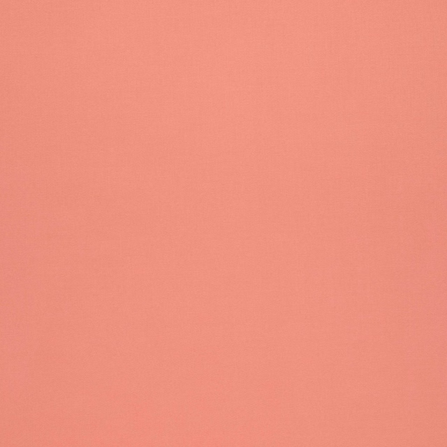 Close-up of plain blush-coral fabric with a fine, softly textured weave