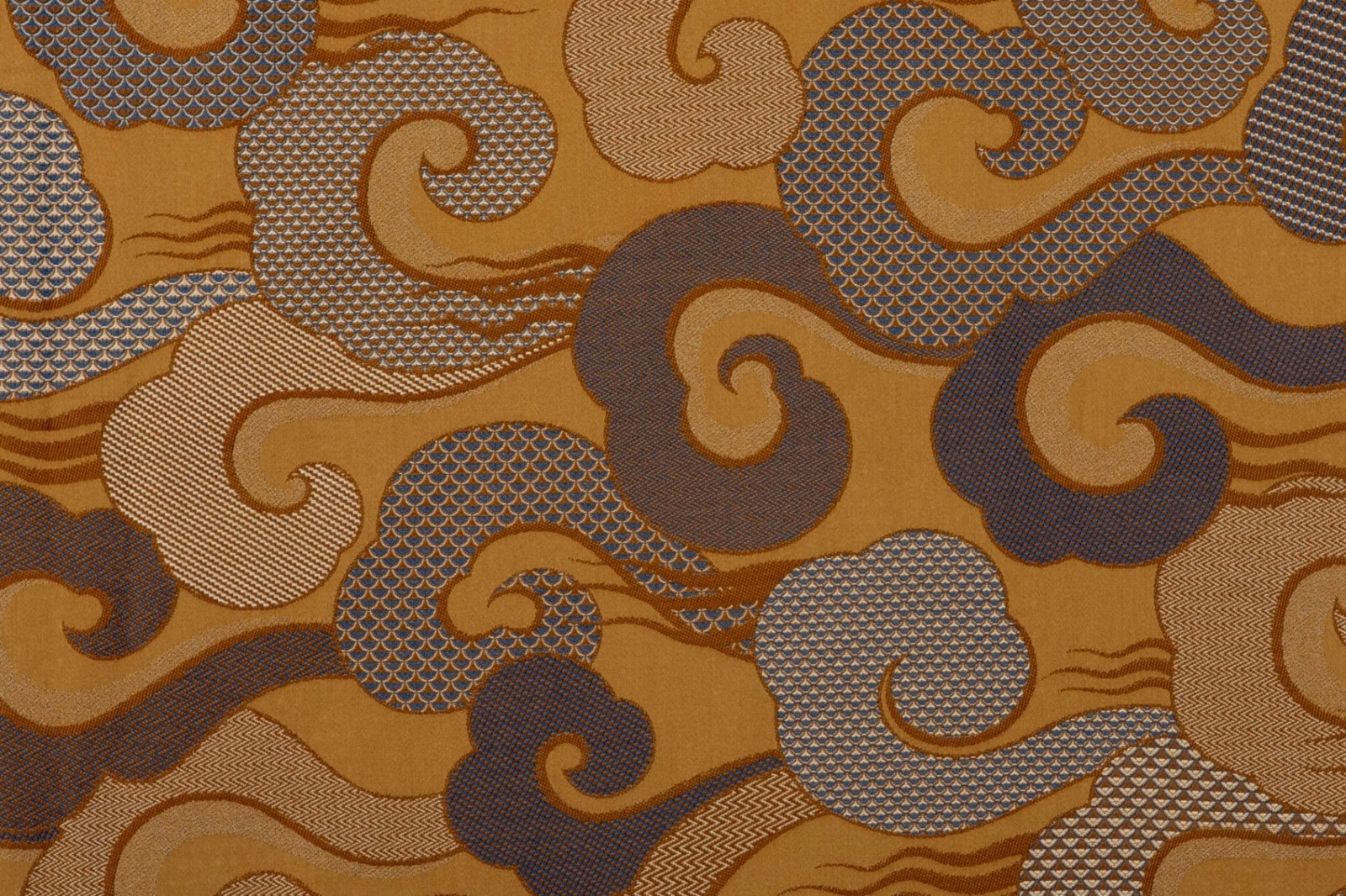 Amber ochre textile with charcoal paisley curls, crosshatch panels and fine wave lines