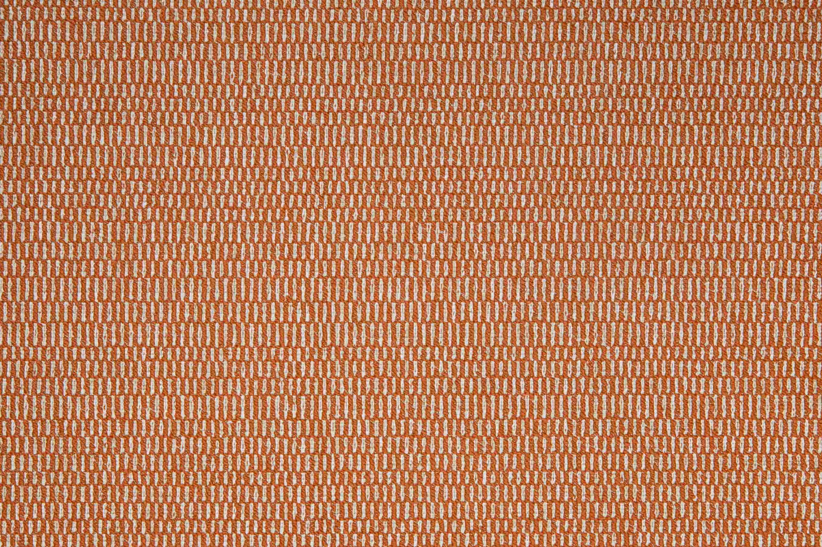 Warm terracotta textile with tiny cream marks in a dense, tactile woven pattern