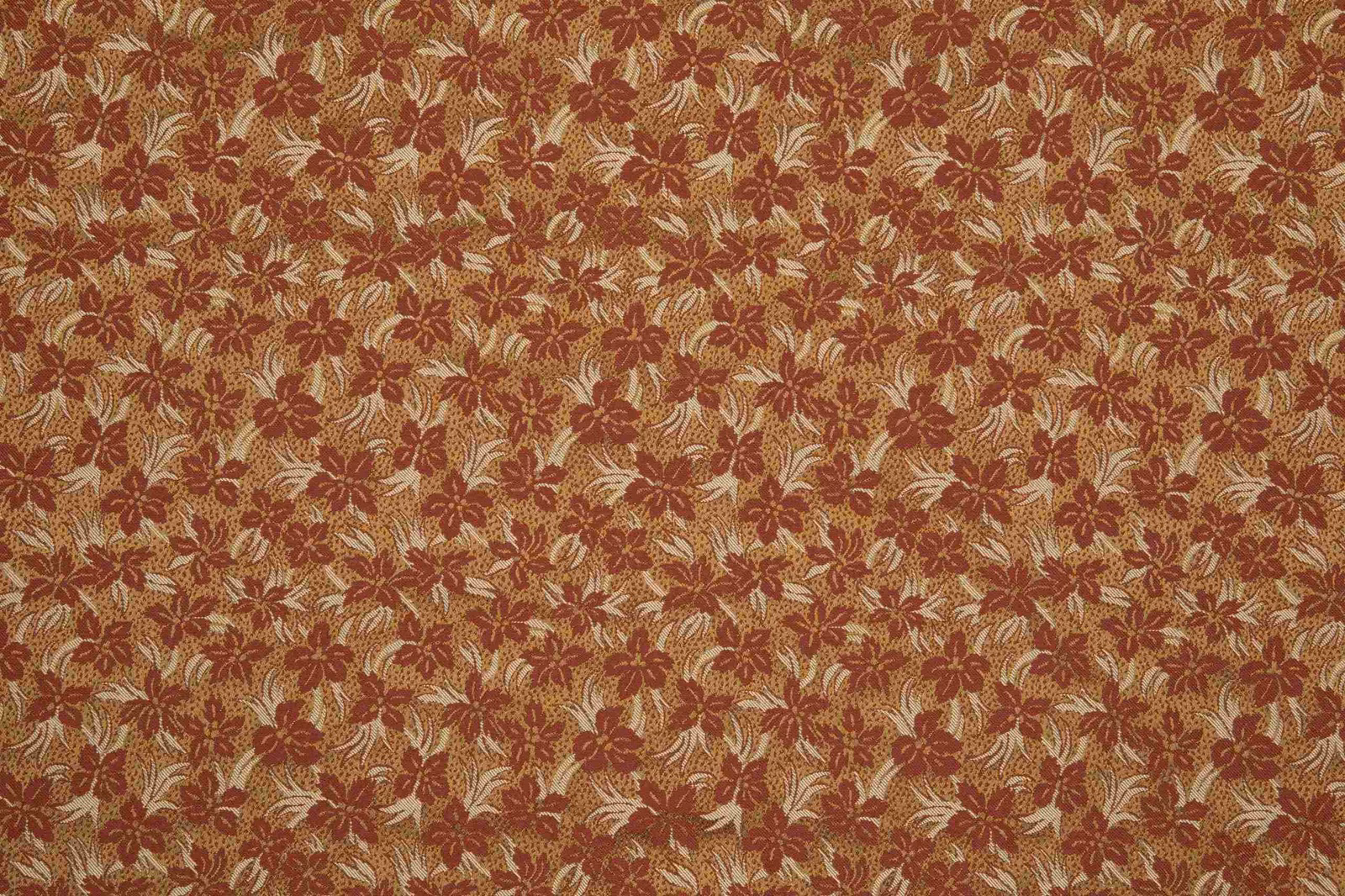 Copper-rust floral fabric with cream leafy sprigs in a textured woven pattern